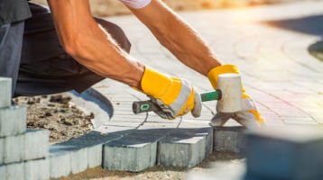Construction worker laying paver blocks